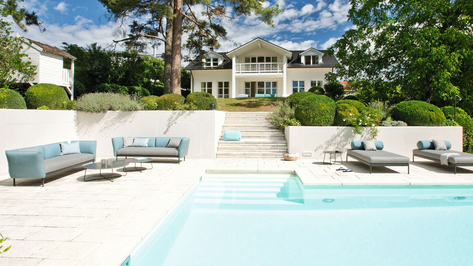 Luxuriöse Kairos Lounge-Möbel und Sonnenliegen von Fischer Möbel an einem privaten Pool. Elegante Outdoor-Sofas in Türkis und Grau vor einer weißen Villa im modernen Landhausstil.