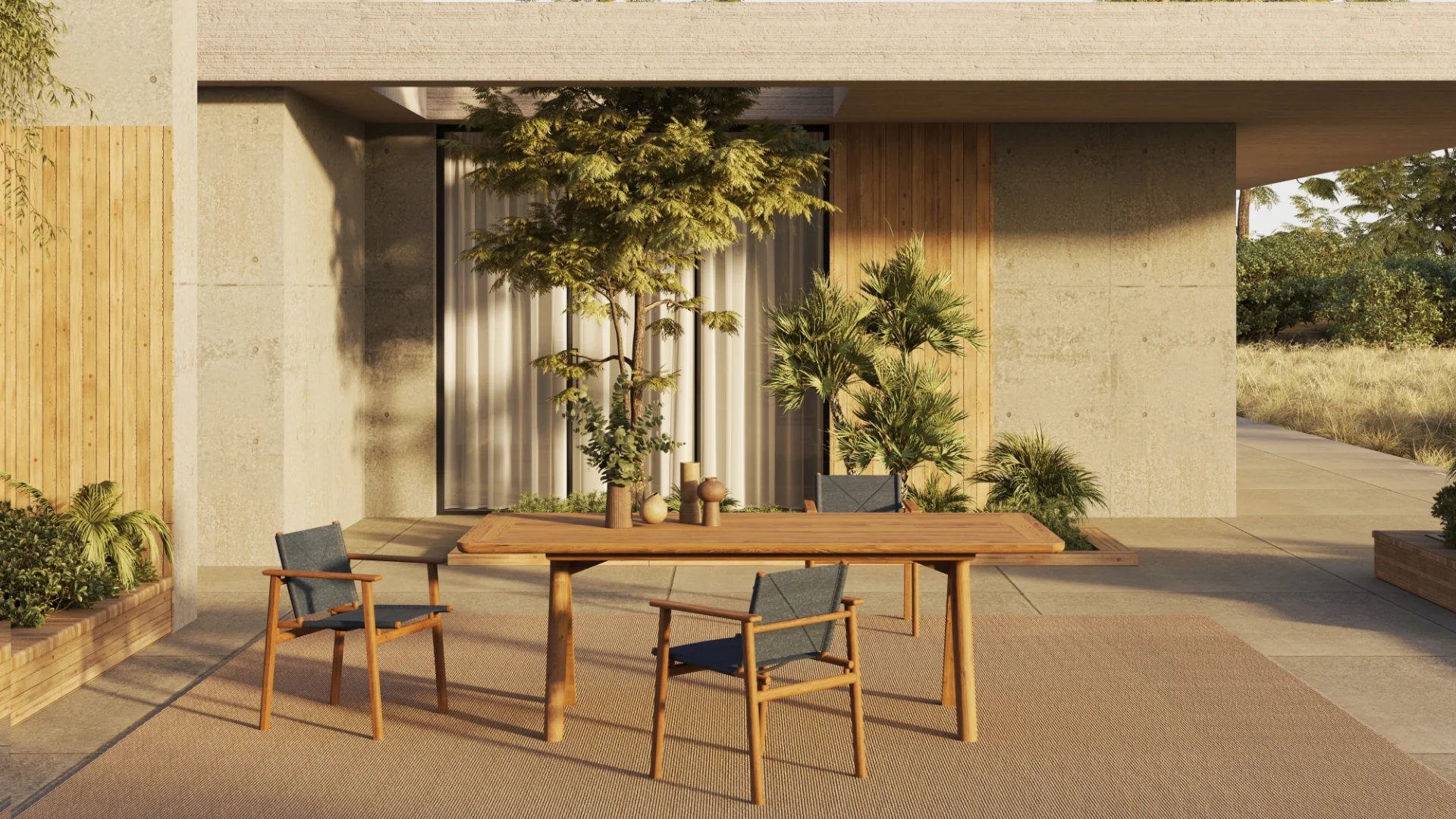 Exklusive Garten-Essgruppe von Fischer Möbel: Hochwertige Tennis Sessel aus Teakholz kombiniert mit dem Dario Esstisch vor moderner Beton-Architektur.