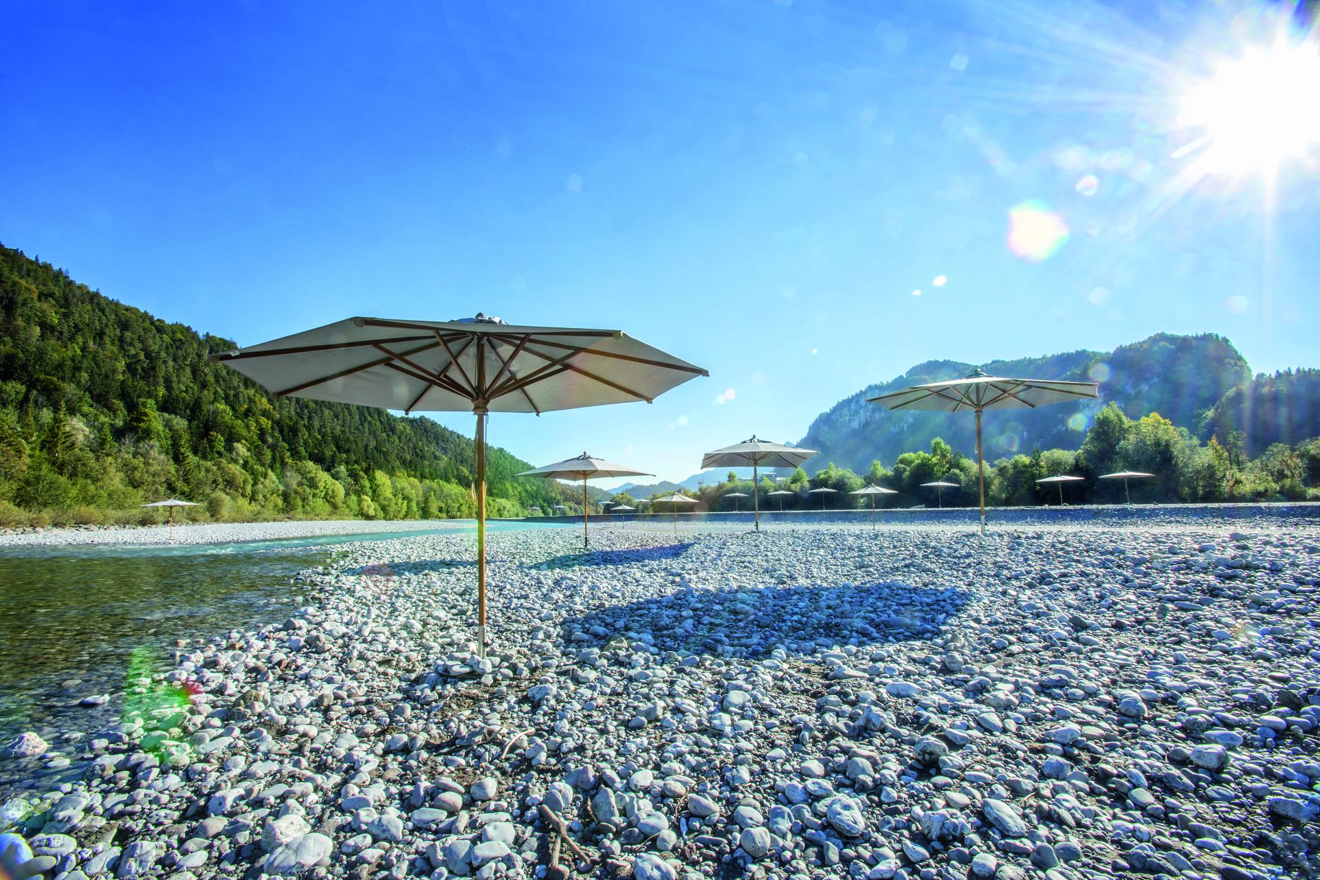 Exklusive Sonnenschirme von Fischer Möbel in einer idyllischen Flusslandschaft. Hochwertiger Sonnenschutz für Garten und Gastronomie im Einklang mit der Natur.
