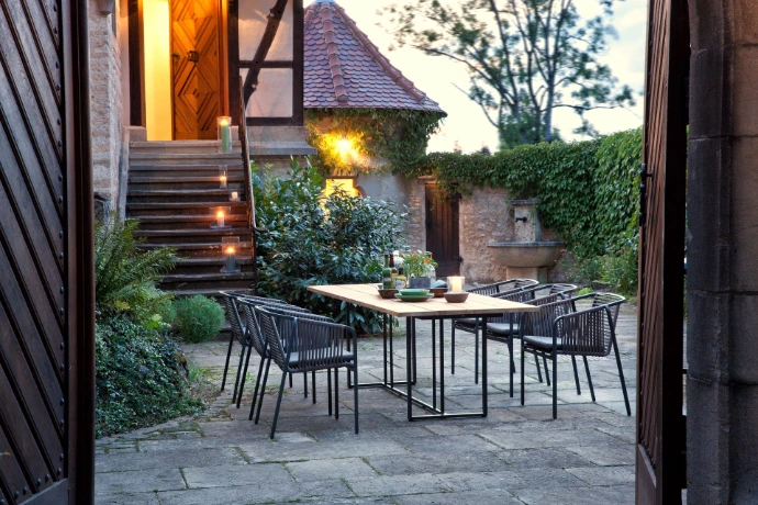 Eleganter Outdoor-Esstisch mit Design Gartenstühlen von Fischer Möbel auf stimmungsvoller Terrasse am Abend